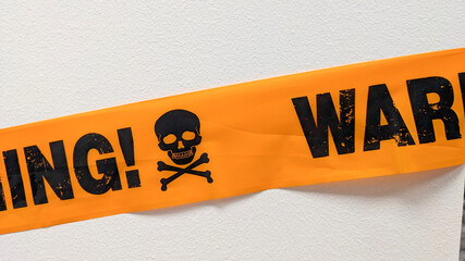 Halloween-themed segment of a bright orange warning tape with partial words that read ING! and WAR