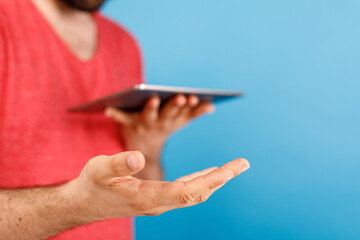 Close-up shot of a person holding a tablet and displaying an open hand. Focus on technology, communication, and the act of sharing. Against a bl