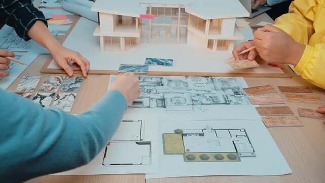A dynamic workspace showcasing architects collaborating on design projects. The image features blueprints, material samples, and various design documents, highlighting creative teamwork. SACTR
