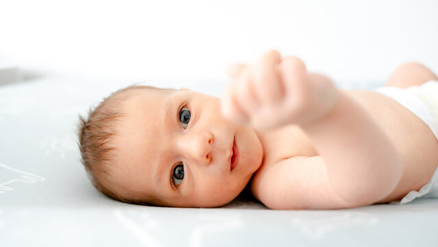 Newborn baby lying on back with curious expression
