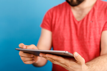 A man holding a tablet computer against a vibrant blue backdrop, showcasing modern technology and communication.