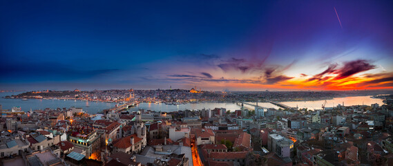A stunning panoramic view of Istanbul, Turkey, at sunset. This cityscape overlooks the Golden Horn and Galata Bridge, with the historic Sultanahmet mosque skyline silhouetted against a colorful sky.
