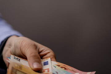 Close-up shot of a person's hand holding euro banknotes, symbolizing cash, finance, and the...