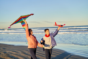 Kids enjoy flying kites and toy planes on a sunny beach