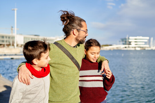 Father enjoying a sunny day at the waterfront with his children