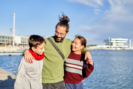 Father enjoying a sunny day at the waterfront with his children