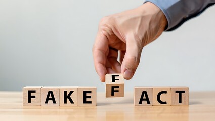 Hand changing wooden blocks from F A K E to F A C T on table fake fact
