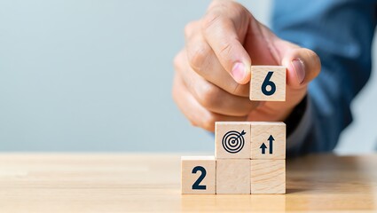 Hand placing wooden block with number 6 on stacked blocks with target and growth icons