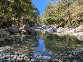 the hiking area of the Restonica Valley with its riverbed with clear pools for bathing in sunshine and blue sky	
