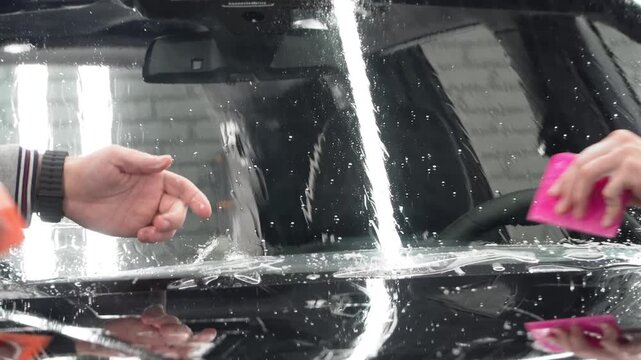 Car wrapping, detailing, tuning and styling. Detailer smoothes PPF. PPF protective film against chips and scratches. A car wrapping specialist applies a polyurethane film to the car. Selective focus.