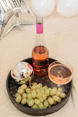 wine bottle, champagne glass, disco ball, and grapes on a tray: festive birthday celebration, luxurious bedroom party, and romantic morning breakfast concept