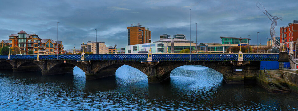 Belfast city historic district skyline over the Queen's Bridge and River Lagan with a view of the Beacon of Hope sculpture and traditional houses and buildings in Northern Ireland, United Kingdom.