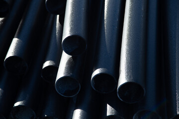 Stacked black pipes with a glossy finish accentuate industrial materials and textures, creating a...