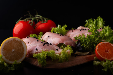 CHICKEN BREAST MEAT ON A WOODEN BOARD WITH SPICES