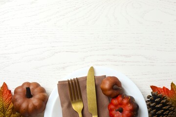 A festive fall table setting with a plate, napkin, cutlery, and pumpkins. Cozy seasonal decor for...