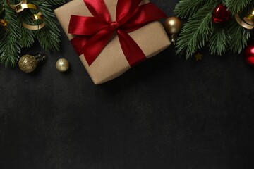 A festive pine arrangement with a gift and glittering ornaments on a dark background. A rich, Merry...