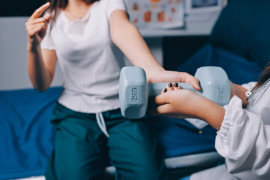 old woman training with physiotherapist using dumbbells at home therapist assisting senior woman with exercises in nursing home elderly patient using dumbbells with outstretched arms no logos no bran - Powered by Adobe