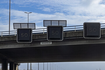 Variable message signs displaying a "50" km h speed limit are mounted beneath a highway overpass on the A2 in the Netherlands, due to congestion.