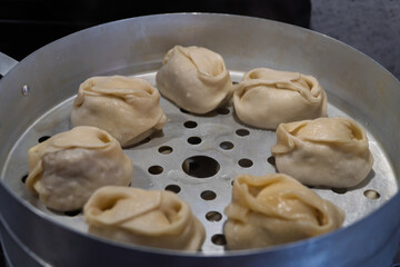 Delicious Manty, posture, khinkali is prepared in a special pot - mantoverde. Dishes of Asian, Buryat, Georgian cuisine. Aluminum steamer for cooking mantas on a stove in a home kitchen. Meat food.