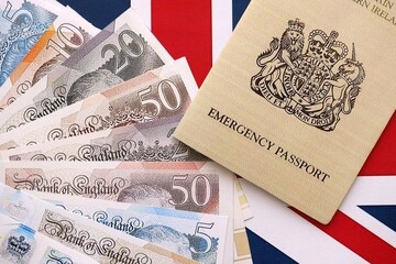 British emergency passport. Yellow color temporary document with british money on flag background...