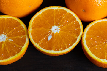Fresh ripe oranges with slices on dark wooden table