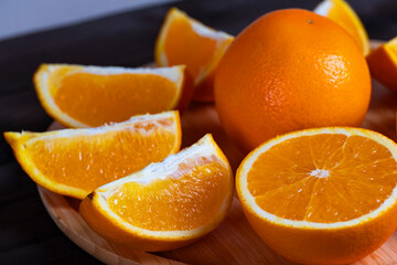 Fresh oranges and slices on wooden plate
