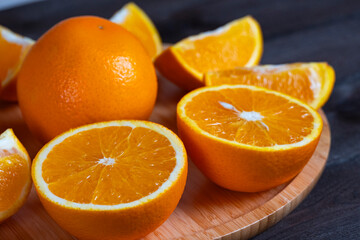 Fresh oranges and slices on wooden plate