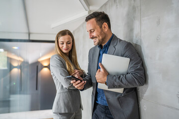 Business colleagues sharing information on smart phone and laptop