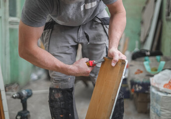 One young worker pulls nails out of wooden boards with pliers.