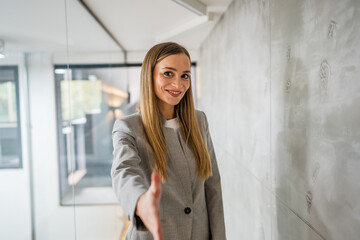 Fototapeta premium Businesswoman extending hand for handshake or welcoming greeting