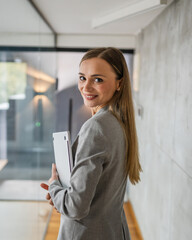 Obraz premium Confident businesswoman walking through modern office building holding laptop