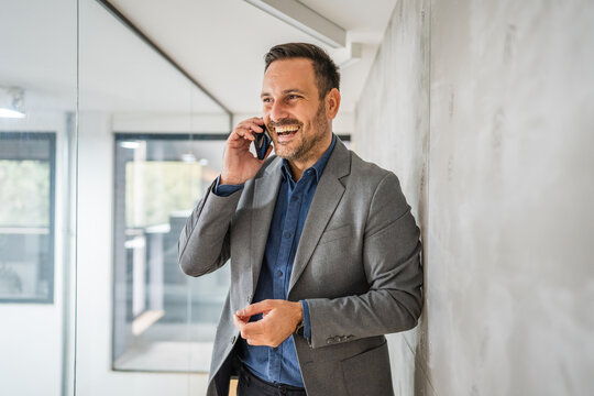 Smiling businessman talking on phone in modern office