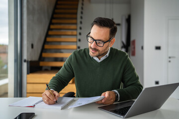 Man working from home making notes and paperwork