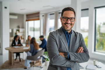 Fototapeta premium Smiling business leader with arms crossed in modern office