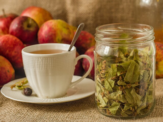 cup of herbal tea with a jar of dried linden leaves on burlap