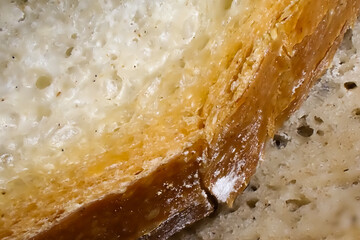 Macro close-up of bread crust and crumb showing golden baked surface and airy interior texture, symbol of artisan baking quality