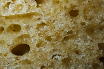 Close-up macro of bread crumb showing porous texture and natural air bubbles, symbol of fresh homemade baking and artisan food quality