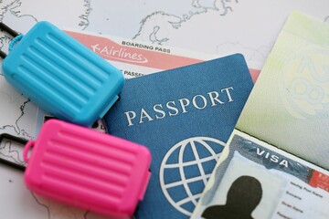 Passport and visa with boarding pass tickets and toy luggage bags on world map close up