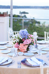 Wedding table decoration with fresh blue and pink flowers, plates and candles