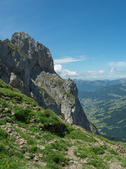 Obraz premium Vertical mountain vista with deep valley and vast green landscape.