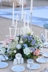 Wedding table decoration with fresh blue and pink flowers, plates and candles
