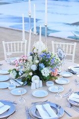 Wedding table decoration with fresh blue and pink flowers, plates and candles