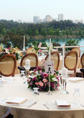 Wedding table decoration with fresh colorful flowers, plates and candles. Wedding decoration with wooden brown chairs 