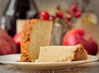 Single piece of pepper jack cheese and a rustic block of another cheese type on a white plate