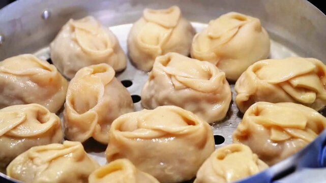 Delicious Manty, posture, khinkali is prepared in a special pot - mantoverde. Dishes of Asian, Buryat, Georgian cuisine. Aluminum steamer for cooking mantas on a stove in a home kitchen. Meat food.