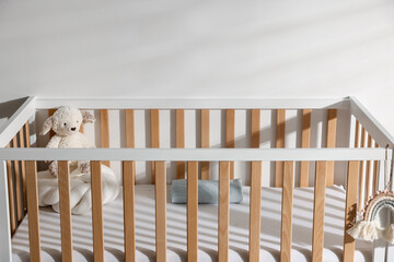 Crib with toy and pillow in baby's room, closeup