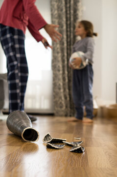 Father scolding naughty child who just broke a vase in the living room, concept of parents and education