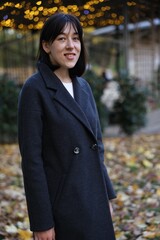 Fototapeta premium Smiling woman wearing coat in autumn park
