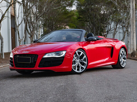 Red Audi R8 V10 Spyder convertible parked on a tree-lined road, Low angle luxury supercar exterior