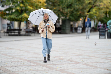Obraz premium Woman walking city street with umbrella and coffee